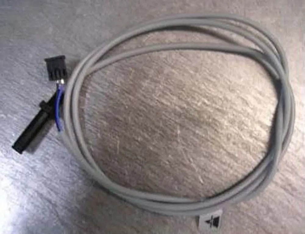 Kabel mit einem Stecker, das zur Rotationsüberwachung von Ölpumpen dient. Ein Produkt der Marke Remeha, auf einer metallischen Oberfläche dargestellt.